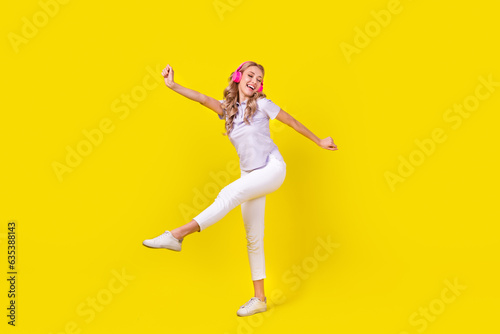 Full length photo of positive woman dressed purple t-shirt listen energetic playlist in headphones isolated on yellow color background
