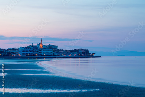 Alba sulla città di Grado, vista dalla spiaggia. Visibile ed illuminato il campanile della basilica si Sant' Eufemia.