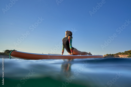 Slim woman practicing yoga in Bhujangasana on paddleboard