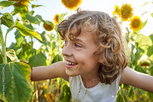 Preteen boy hiding among sunflowers