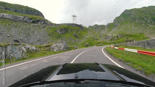 Car ride Point Of View, The Majestic Transfagarasan Mountain Road in Romania With A Black sport Car Bonnet In The Foreground And Tall Mountain Peaks. POV shot of sport car drives along the majestic