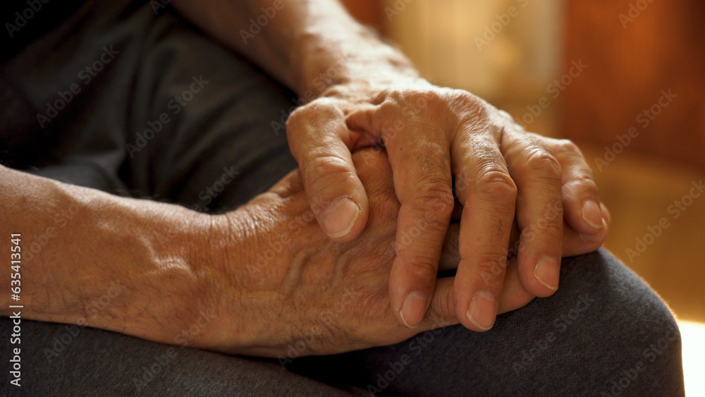 Fototapeta premium The older man's hands are on his knees, waiting.
