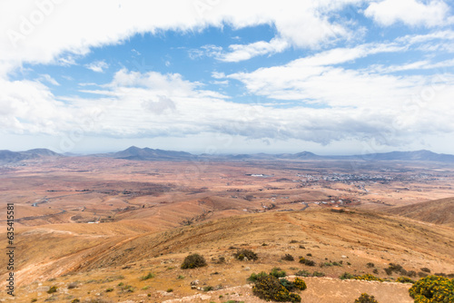 Desertic landscape of the interior of Fuerteventura island. Rocky hills with white sand. Sky with big white clouds. Sunny day Fuerteventura  Canary Islands  Spain.