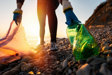 Conservation of ecology and Earth Day. A volunteer collects plastic bottles by the sea. Concept of coastal cleanup and global environmental pollution