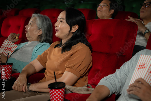 Group of asian senior friends watching comedy movie and laugh at the cinema with popcorn