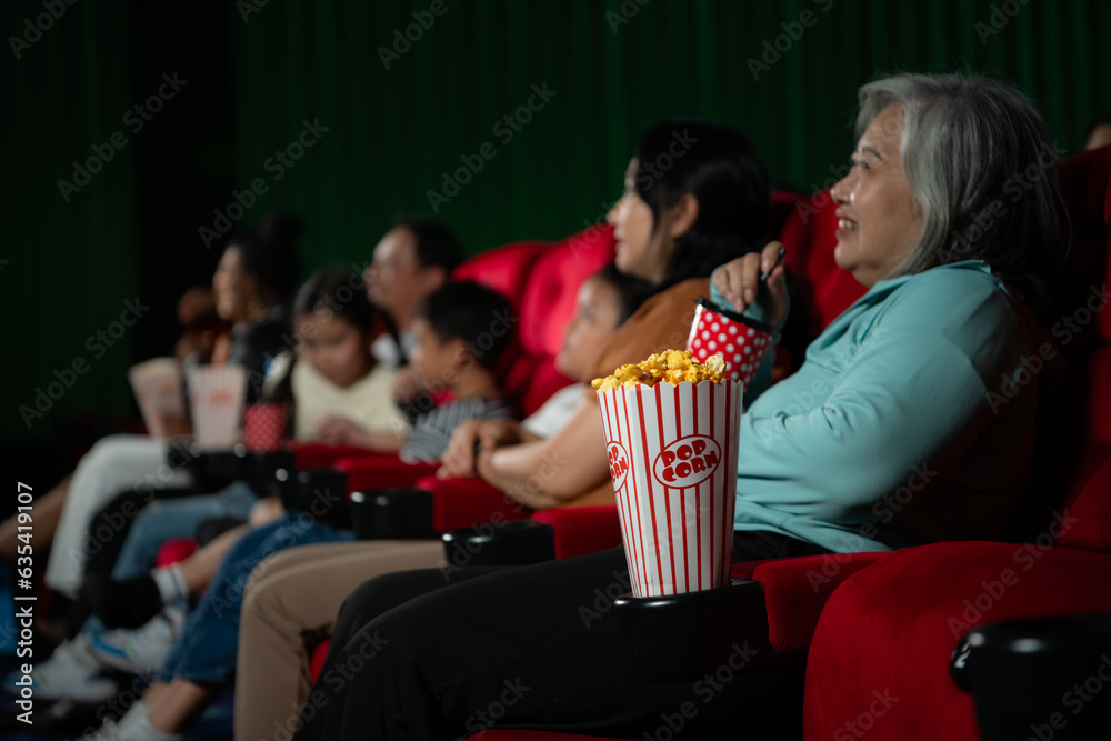 Asian mother and daughter watching movie in cinema. Family time concept.