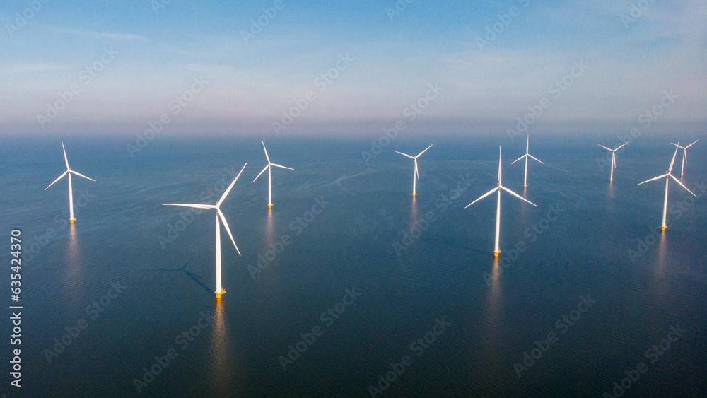 Windmill park with clouds and a blue sky, wind mill turbines in the ocean aerial view with wind turbine Flevoland Netherlands Ijsselmeer. Green Energy production in the Netherlands Windmill park with clouds and a blue sky, wind mill turbines in the ocean aerial view with wind turbine Flevoland Netherlands Ijsselmeer. Green Energy production in the Netherlands