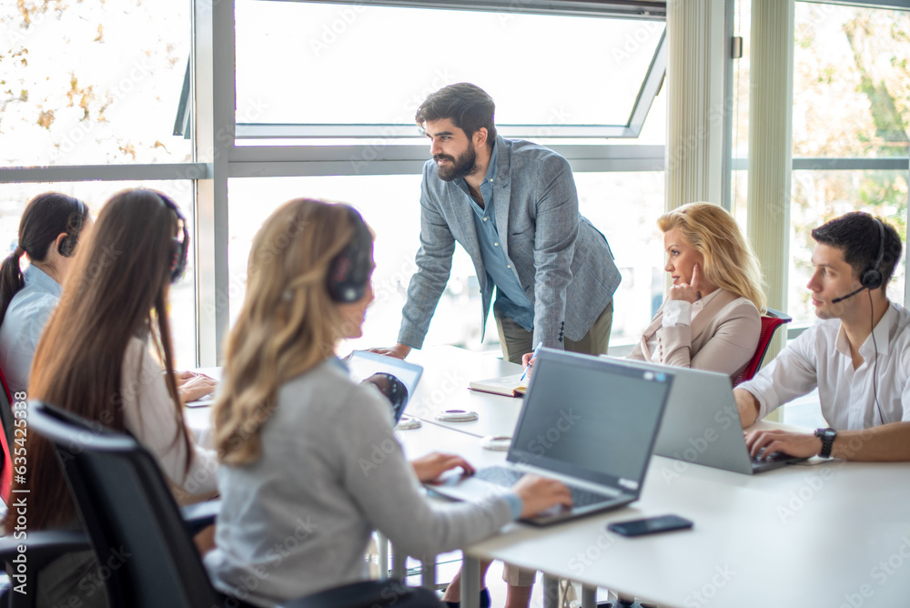 Handsome male supervisor with business team having a meeting at desk in call center. Handsome male supervisor with business team having a meeting at desk in call center.