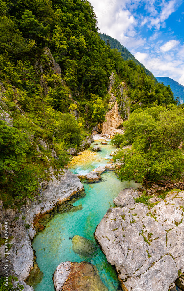 Idyllic scenery at Soca or Isonzo river (Emerald River) in Slovenia is a wild alpine river with crystal clear water and turquoise green color with rapids and waterfalls. Seen from a suspension bridge.