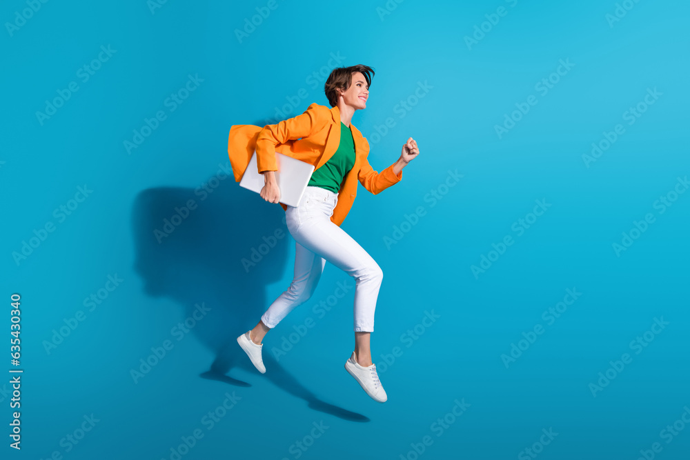 Profile side photo of excited cheerful active lady wear stylish orange clothes go fast empty space isolated on blue color background