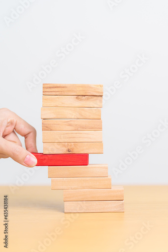 woman hand pulling wood domino blocks on table. Crisis, fall Business, Risk management, Economic recession, Strategy and solutions concept