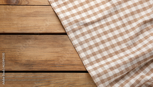 Beige checkered tablecloth on wooden table, top view. Space for text