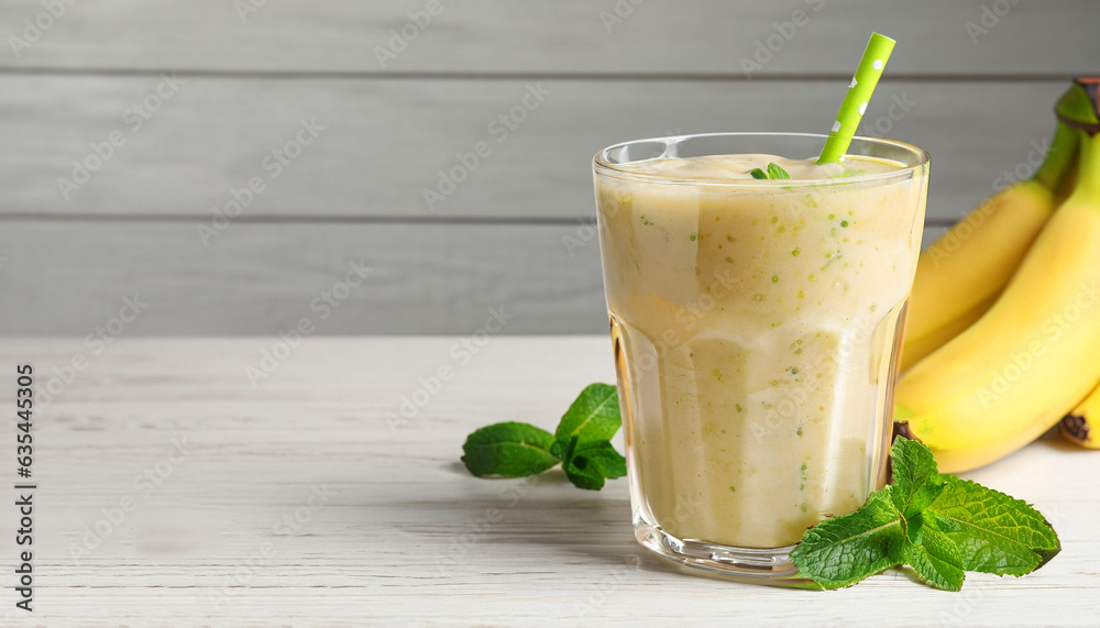 Glass of tasty smoothie, mint and fresh bananas on white wooden table, space for text. Banner design Glass of tasty smoothie, mint and fresh bananas on white wooden table, space for text. Banner design