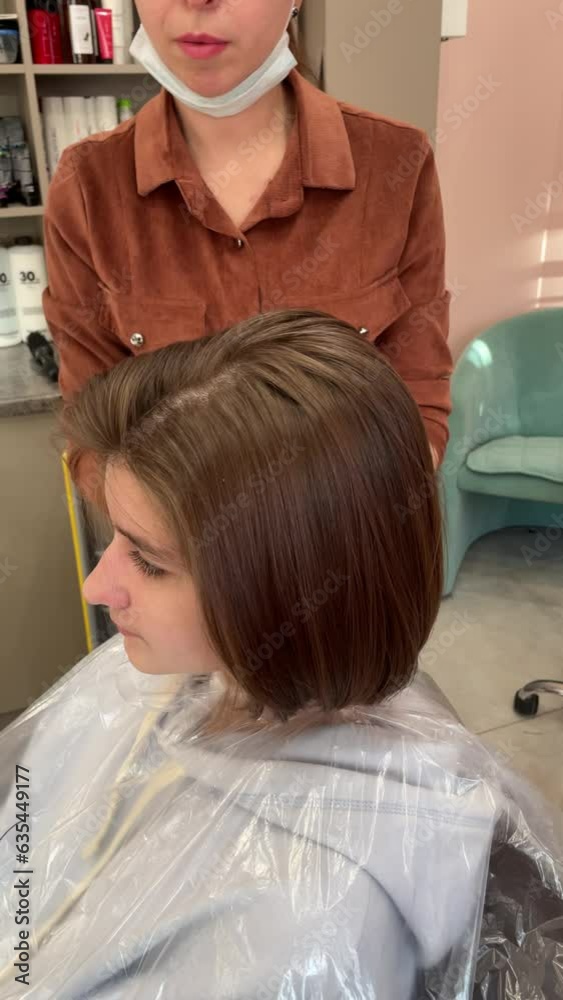 A female hairdresser makes a fashionable beautiful hairstyle for a cute baby girl in a modern barbershop, hairdressing salon. A hairdresser makes a hairstyle for a young girl in a barber shop. The con