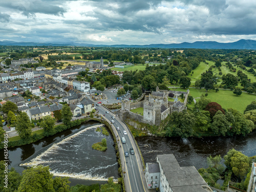 Aerial view of Cahir castle and town in Ireland with Tower House, outer castle, circular, rectangular towers, banquette hall, guarding the crossing on the River Suir with a waterfall and golf course photo