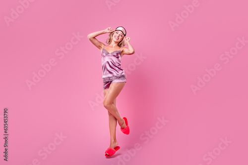 Full length photo of excited cheerful lady dressed silky sleepwear jumping high empty space isolated pink color background