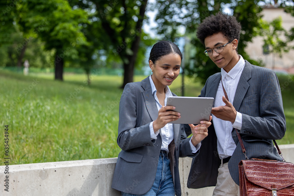 Two colleagues looking involved while watching something on tablet