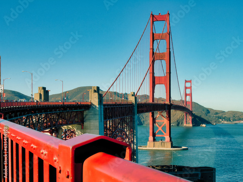 A unique view of the San Francisco Golden Gate Bridge, a suspension bridge spanning the one-mile-wide strait connecting San Francisco Bay and the Pacific Ocean. The sky and water are deep blue. photo