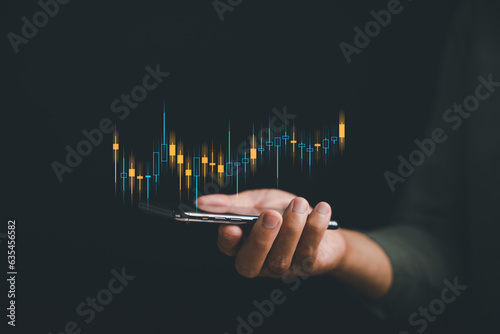 Successful trader using mobile phone for online stock trading, analyzing market data and making strategic investment decisions. Technology financial growth concept. Technical price graph and indicator