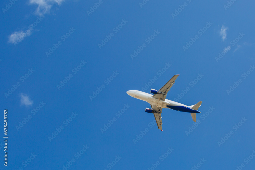 White- blue passenger airplane flying in the sky amazing clouds in the background White- blue passenger airplane flying in the sky amazing clouds in the background
