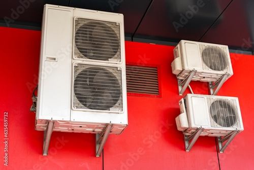 Obraz na plátne Air conditioners, compressors for air cooling hanging on street on red backgroun