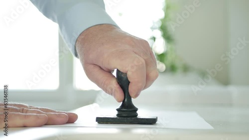 Blurred Shooting with a Businessman Approving a Document Using a Rubber Stamp. Man Checking and Stamping a Contract or a Letter.