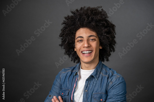 Waist up of a curly-haired young man on grey background