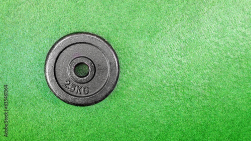 Top view of a 2.5 kg dumbbell weight on a green grass floor background