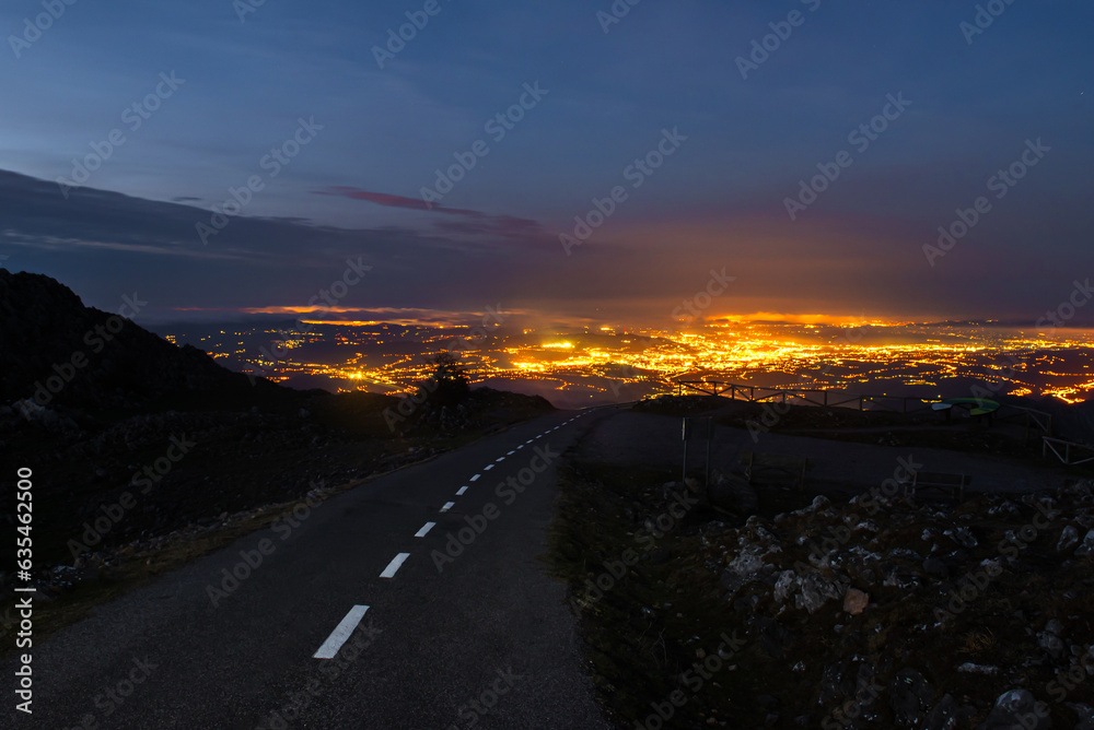 mountain road at night with the lights of a city in the background. Night view of the city of Oviedo, Asturias, Spain, from the top of a mountain. travel at night