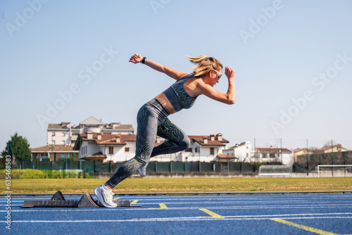 Woman ready to sprint start in athletics - Sprinter girl in starting blocks ready for the race on the track