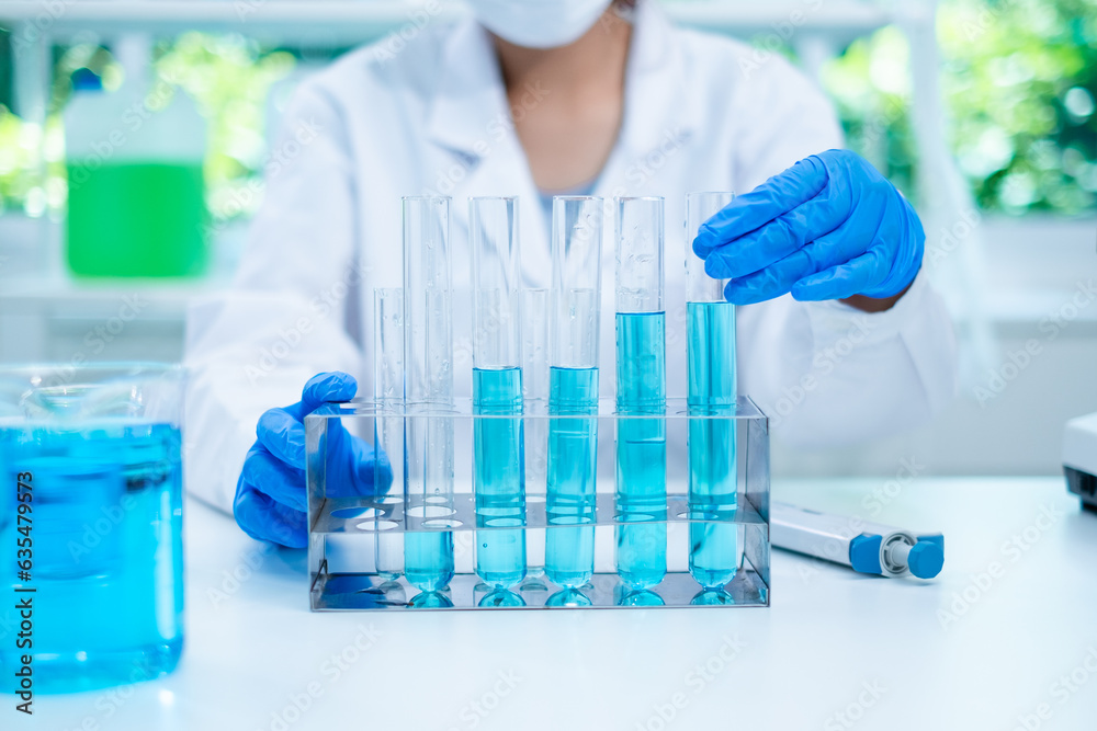 Close up of scientist's hand is holding a blue chemical substance in laboratory. Concept of checking quality of sample liquid or biotechnology and medicine research, examining, inspection or discovery