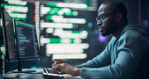 Black Male Programmer Working in Monitoring Room, Surrounded by Big Screens Displaying Lines of Programming Language Code. Portrait of Man Creating a Software. Futuristic Coding Concept.