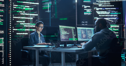 Portrait of Two Programmers Working in a Monitoring Control Room, Surrounded by Big Screens Displaying Lines of Programming Language Code. Portrait of Diverse Developers Creating a Software, Coding