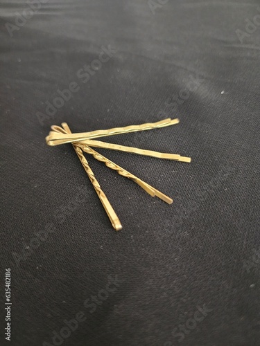 Four luxury elegant hair clips or bobby pins in gold color in black background photo