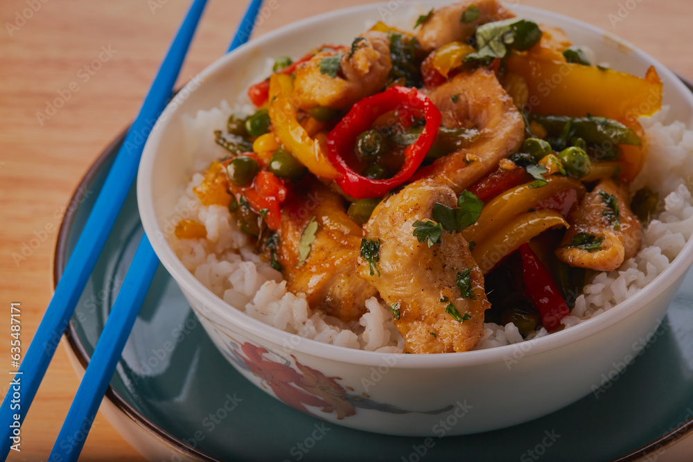 Sweet chilli chicken stir fry with white rice and some chopsticks resting at the side. Sweet chilli chicken stir fry with white rice and some chopsticks resting at the side.