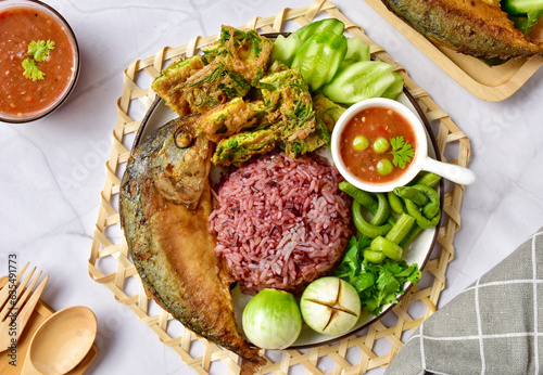 Thai spicy shrimp paste dipping sauce ( Nam prik kapi )with cooked riceberry rice and fried mackerel fish and fried egg with climbing wattle and vegetable set. photo