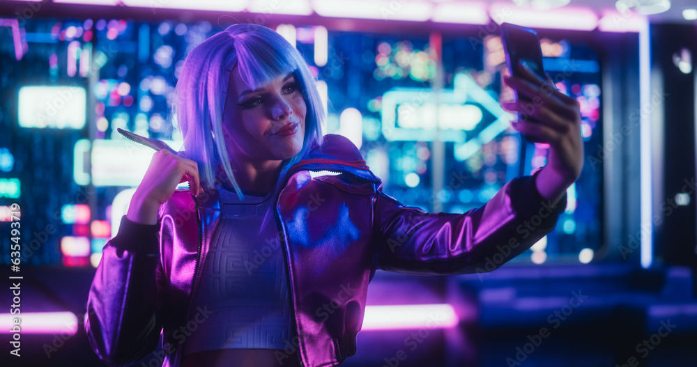 Portrait of a Beautiful Content Creator Taking Selfie Photos on Smartphone. Young Female Making Cyberpunk Cosplay in Stylish Clothes and Blue Hair. Gamer Female Standing in Futuristic Neon Room Portrait of a Beautiful Content Creator Taking Selfie Photos on Smartphone. Young Female Making Cyberpunk Cosplay in Stylish Clothes and Blue Hair. Gamer Female Standing in Futuristic Neon Room