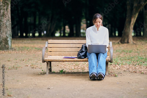 公園のベンチに座りパソコンを使う女性