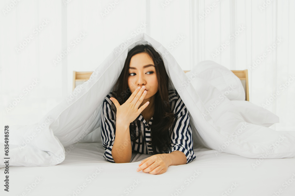 Young woman smelly mouth gingivitis caused by tooth decay : Asian woman laying in bed just waking up in the morning covering her mouth with her hand to prevent bad breath from causing annoyance. Young woman smelly mouth gingivitis caused by tooth decay : Asian woman laying in bed just waking up in the morning covering her mouth with her hand to prevent bad breath from causing annoyance.