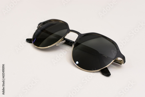 Anteojos o gafas de sol en metal negro plateado apoyados hacia arriba. Salud visual. Fotografía en fondo blanco y desenfoque