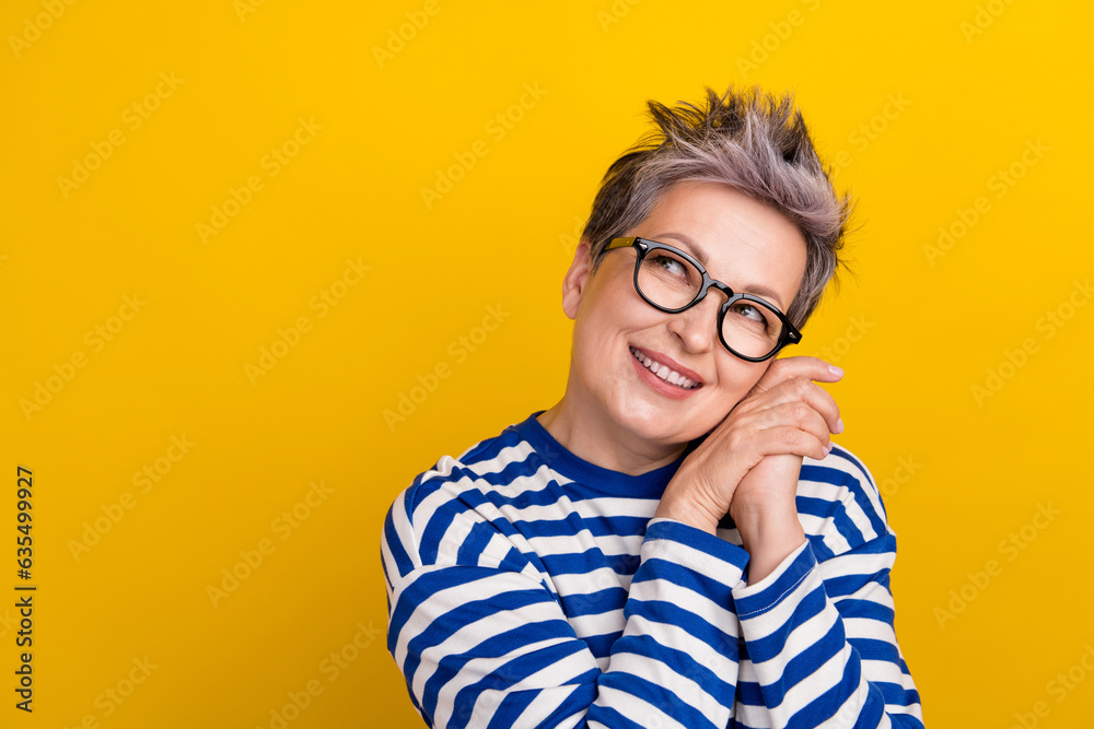Portrait photo of elderly grandmother hands together cute affectionate lady looking empty space glad isolated on yellow color background