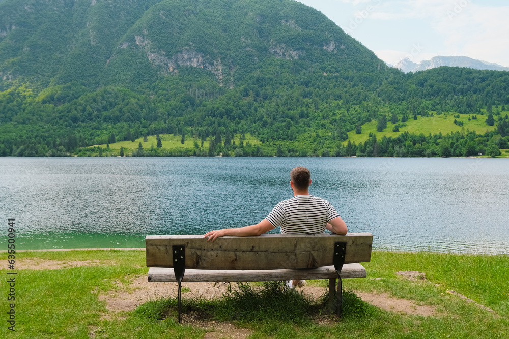 man relaxing on a bench with a mountains view