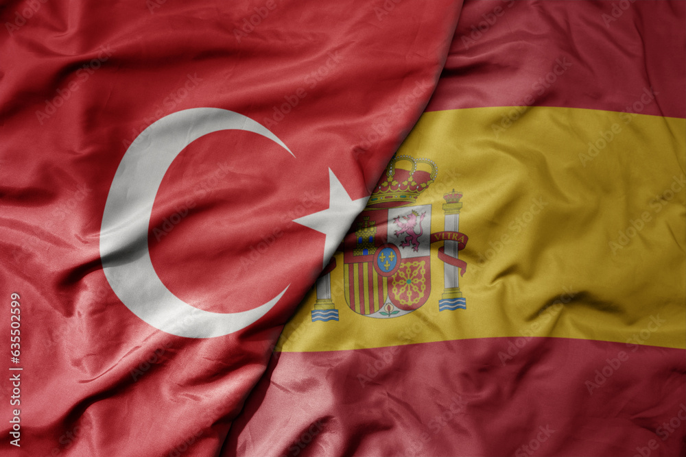 big waving national colorful flag of turkey and national flag of spain .