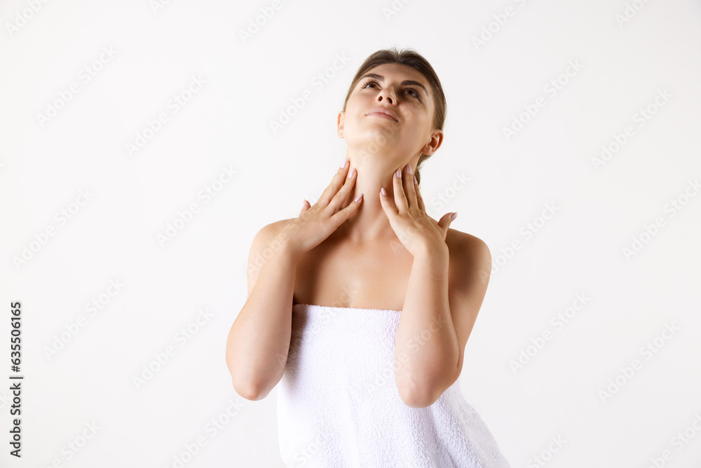 Young woman in towel after shower taking care after face and body skin against white studio background. Concept of female beauty, skin care, cosmetology and cosmetics, health, ad Young woman in towel after shower taking care after face and body skin against white studio background. Concept of female beauty, skin care, cosmetology and cosmetics, health, ad