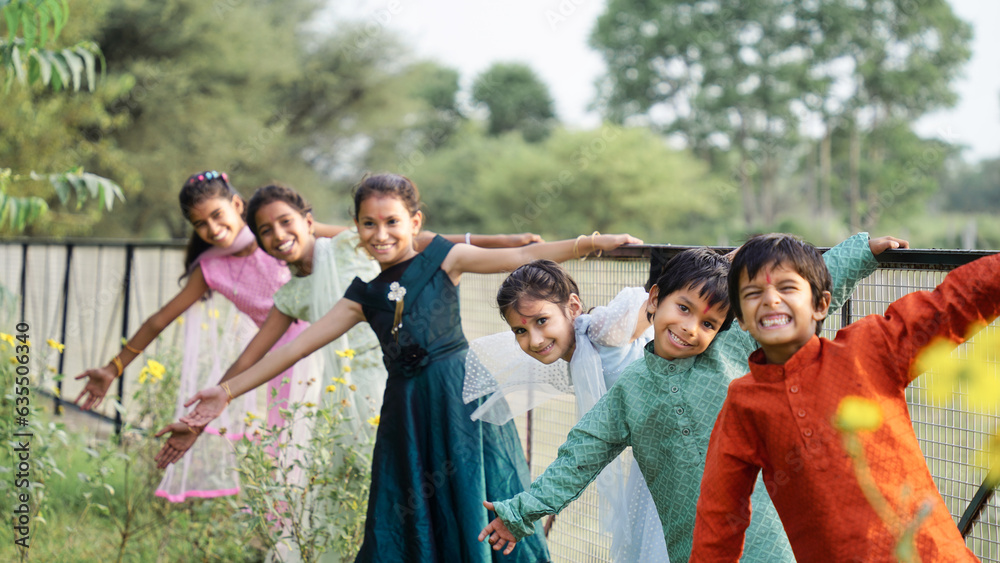 Group of happy playful Indian children playing outdoors in spring park. Asian kids Playing in garden. Summer holidays.