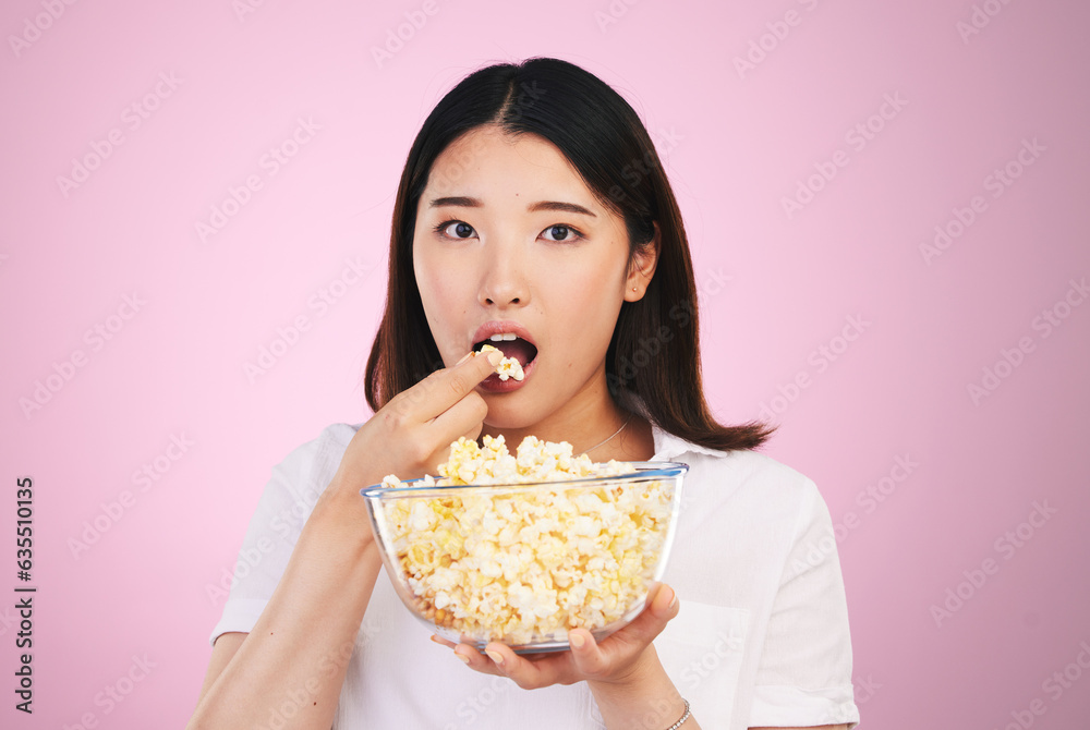 Popcorn, hungry and woman portrait eating a movie snack in a studio with watching tv and food. Pink background, Asian female person and surprise with chips in a glass bowl with film and series Popcorn, hungry and woman portrait eating a movie snack in a studio with watching tv and food. Pink background, Asian female person and surprise with chips in a glass bowl with film and series