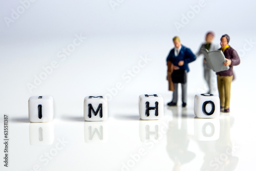 imho word or concept made by white letter cubes on white and gray background with miniature figurines, in my honest humble opinion abbreviation