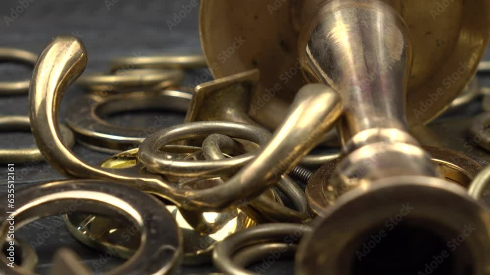 Various household items made of brass and bronze lie on a dark wooden board