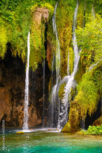 Waterfalls and cascades in natural reserve in Plitvice, Croatia on a sunny summer day. Colorful scenery with lush vegetation, clear lakes and turquoise water. Popular tourist attraction and wonder.