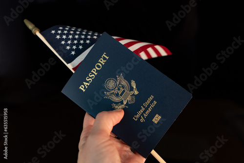 Hand holding a passport of USA and  flag of USA on a black blurred background